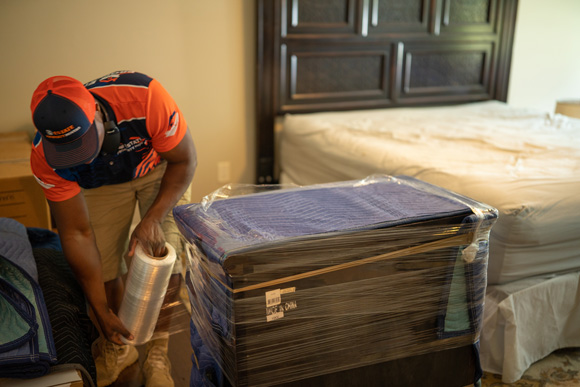 Movers carefully wrapping a dresser for a safe move