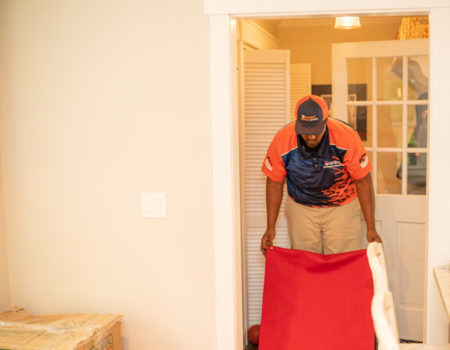 professional mover laying down a red sheet in preparation for Specialty Movers, Gun Safe Movers, and Piano Movers in Duluth, GA