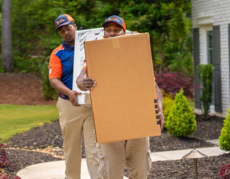 movers holding boxes while providing services like Luxury Corporate Commercial Movers in Peachtree Corners, GA