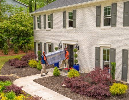 two movers carrying a gun safe out of a house while providing services such as Specialty Movers: Piano Mover and Gun Safe Movers in Alpharetta, GA